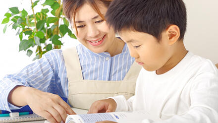 読書をしている子どもを見守るエプロン姿の女性