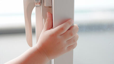 窓枠にかかる子どもの手