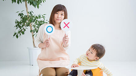 赤ちゃんとマルとバツのマークを持つ女性