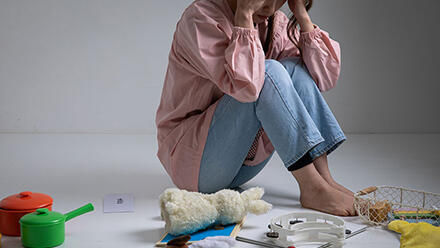 膝を抱えて座る保育士