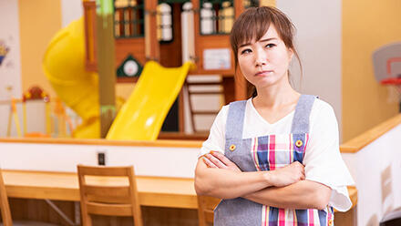 腕組みをする保育士