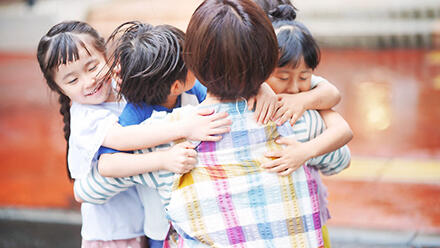 子どもたちとスキンシップをする保育士