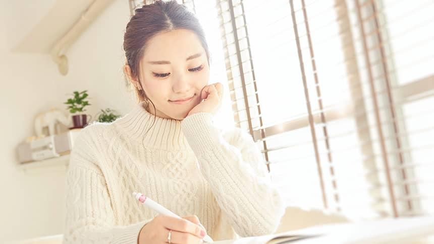 机に向かう白いセーターの女性