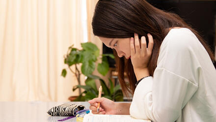 頬杖をついて机に向かう女性