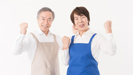 エプロン姿でガッツポーズをするシニアの男女