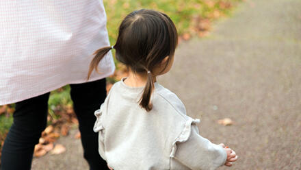 保育士の隣を歩く小さな女の子