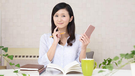 スマホを片手に勉強する女性