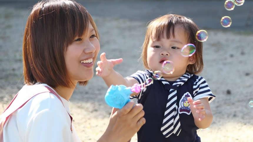 シャボン玉で遊ぶ保育士と園児