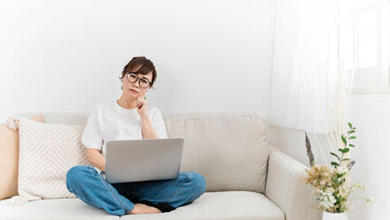 ノートパソコンを抱えて悩む女性