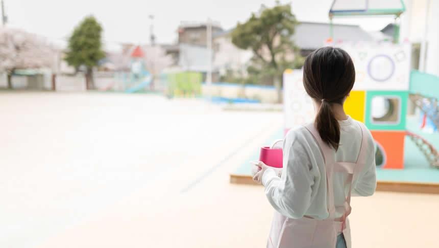 園庭を見つめる保育士